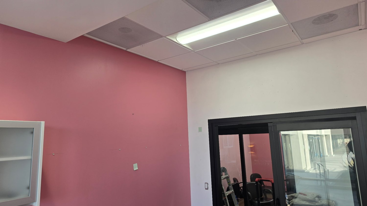 Pink accent wall with patched spots near a black-framed doorway