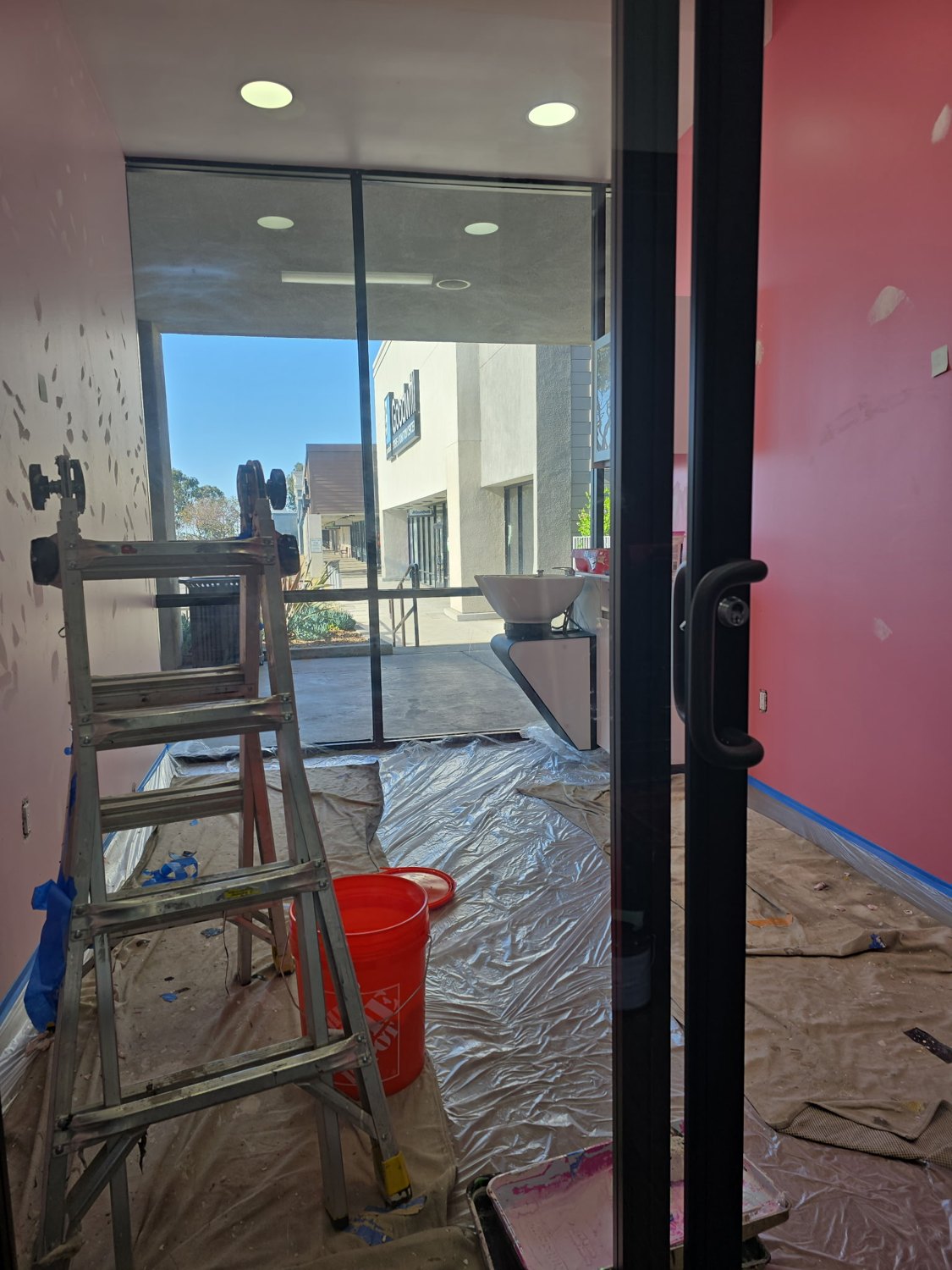 Entry area with a ladder, floor coverings, and painting supplies