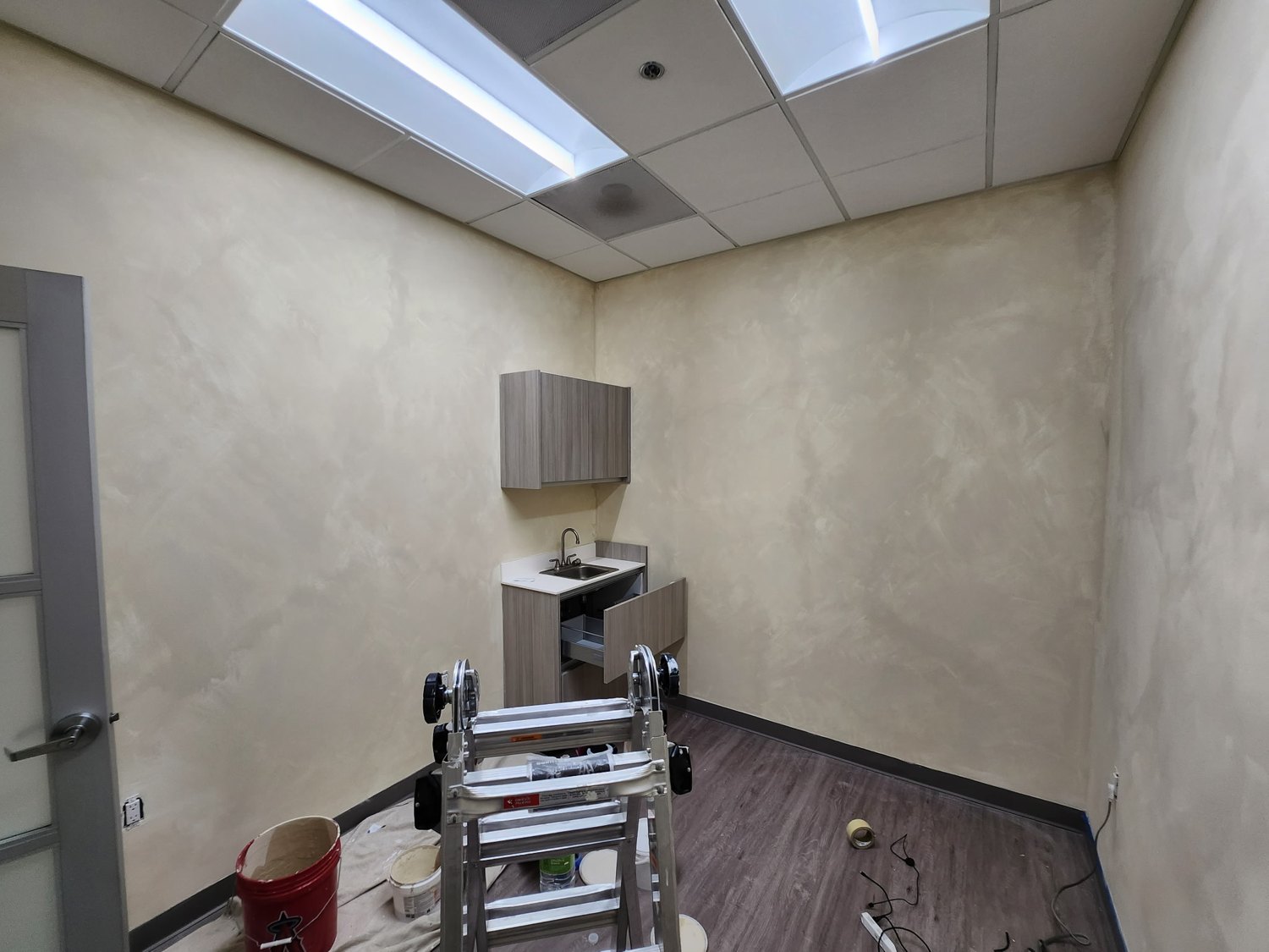 Interior with covered flooring, worked walls, and painting equipment