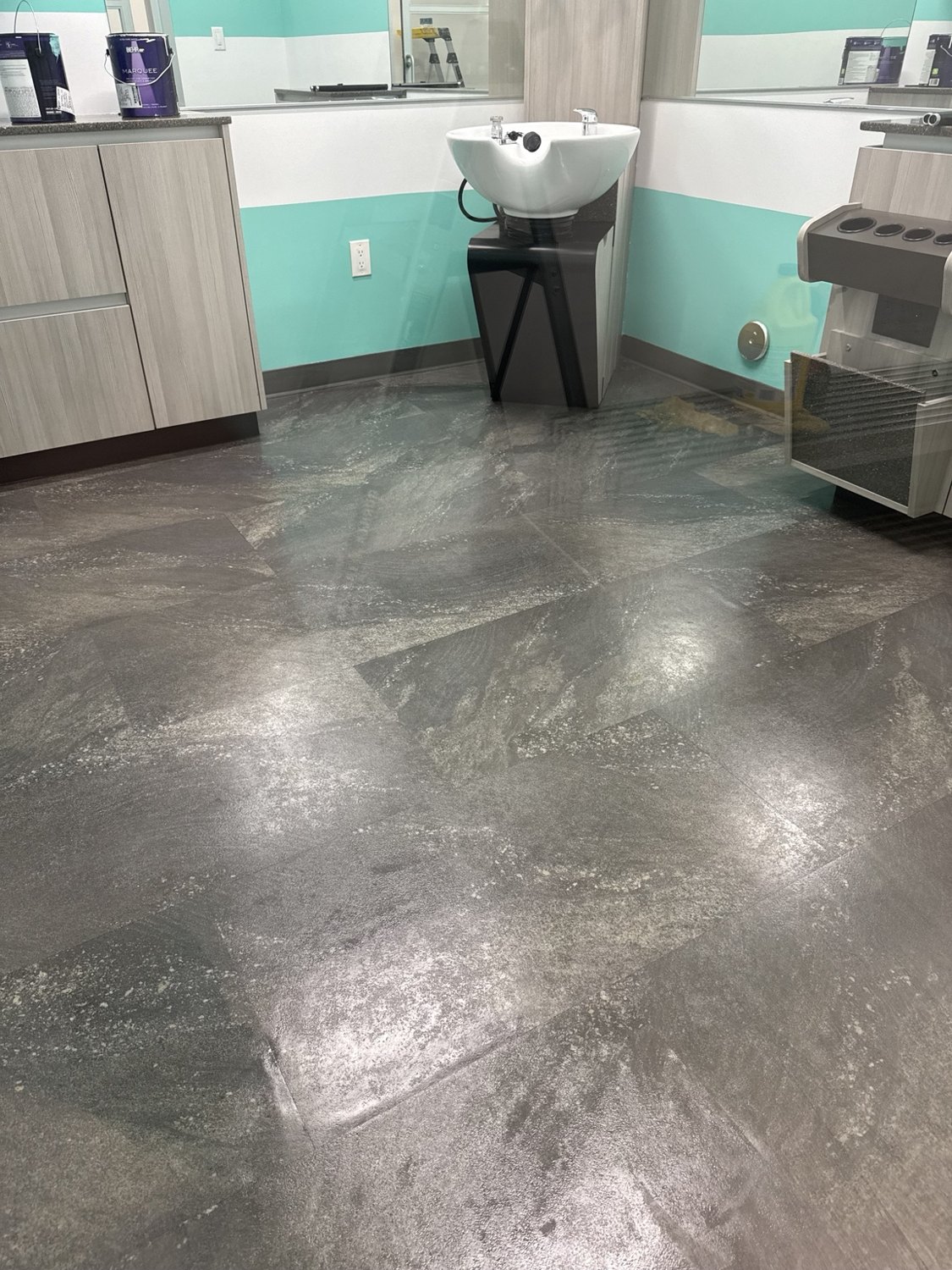 Salon suite floor with a mottled gray appearance beside a sink and cabinetry