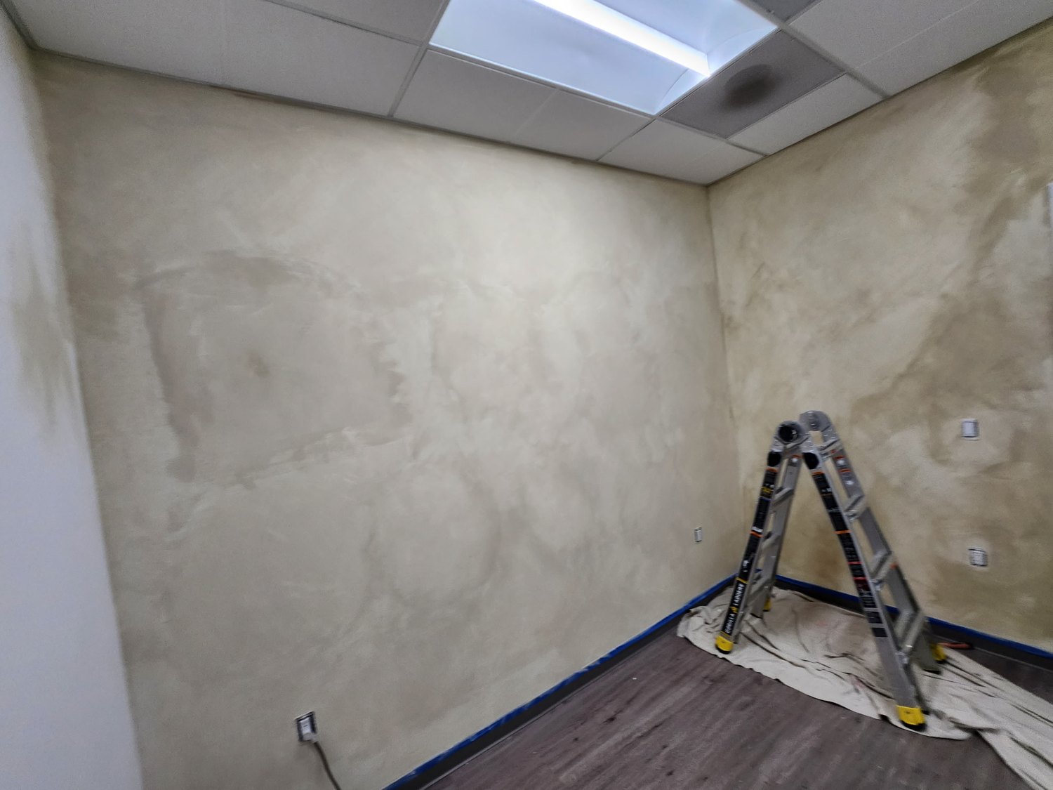 Room with worked wall surfaces, taped edges, and a ladder