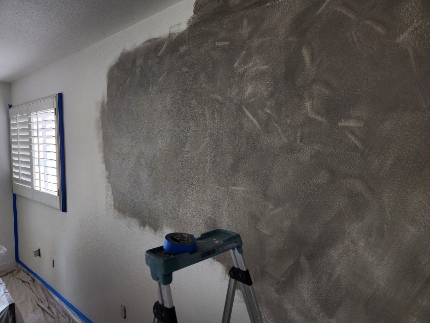 Interior wall with a textured finish beside a shuttered window